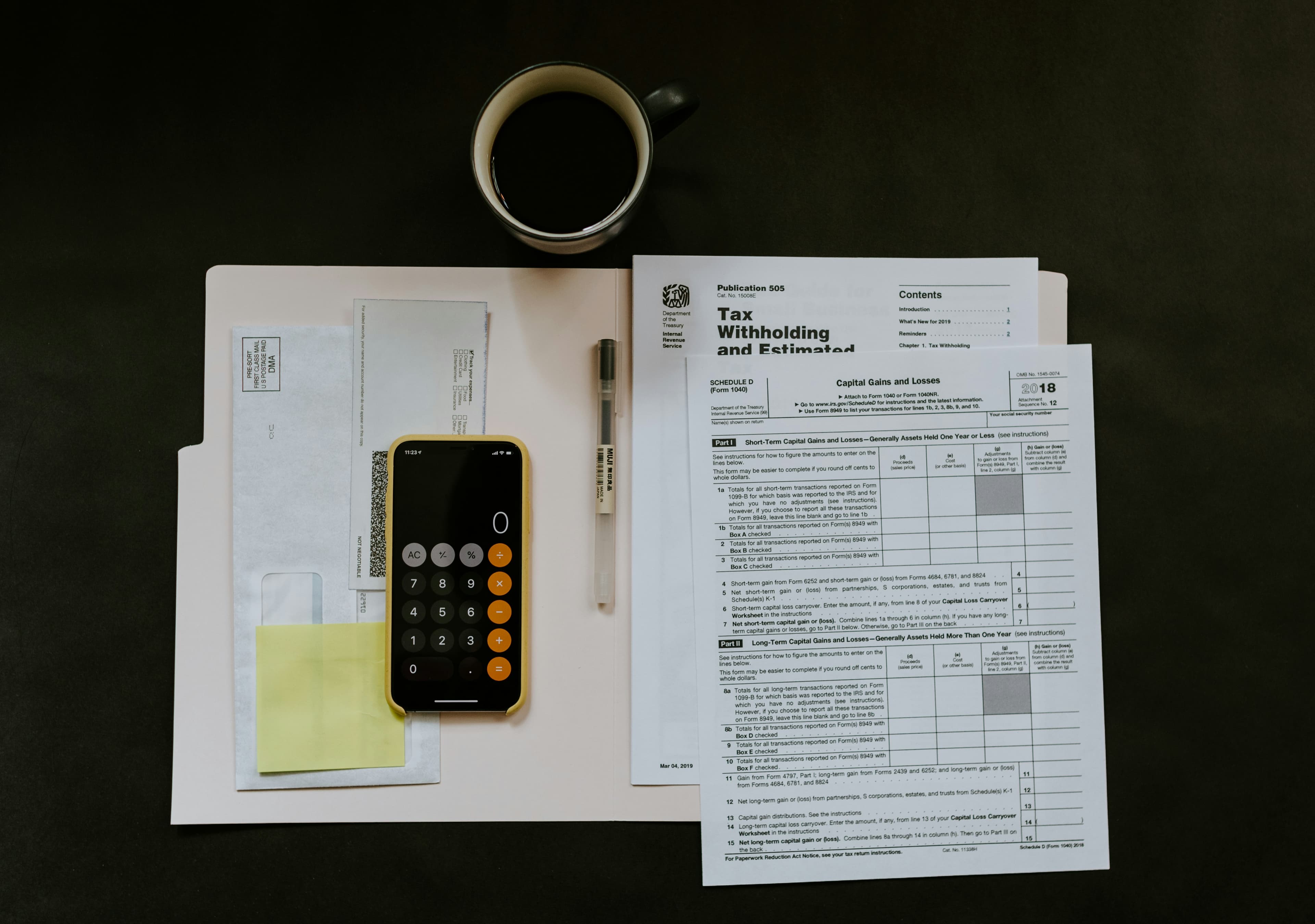 IRS tax forms with a phone calculator and coffee on a desk