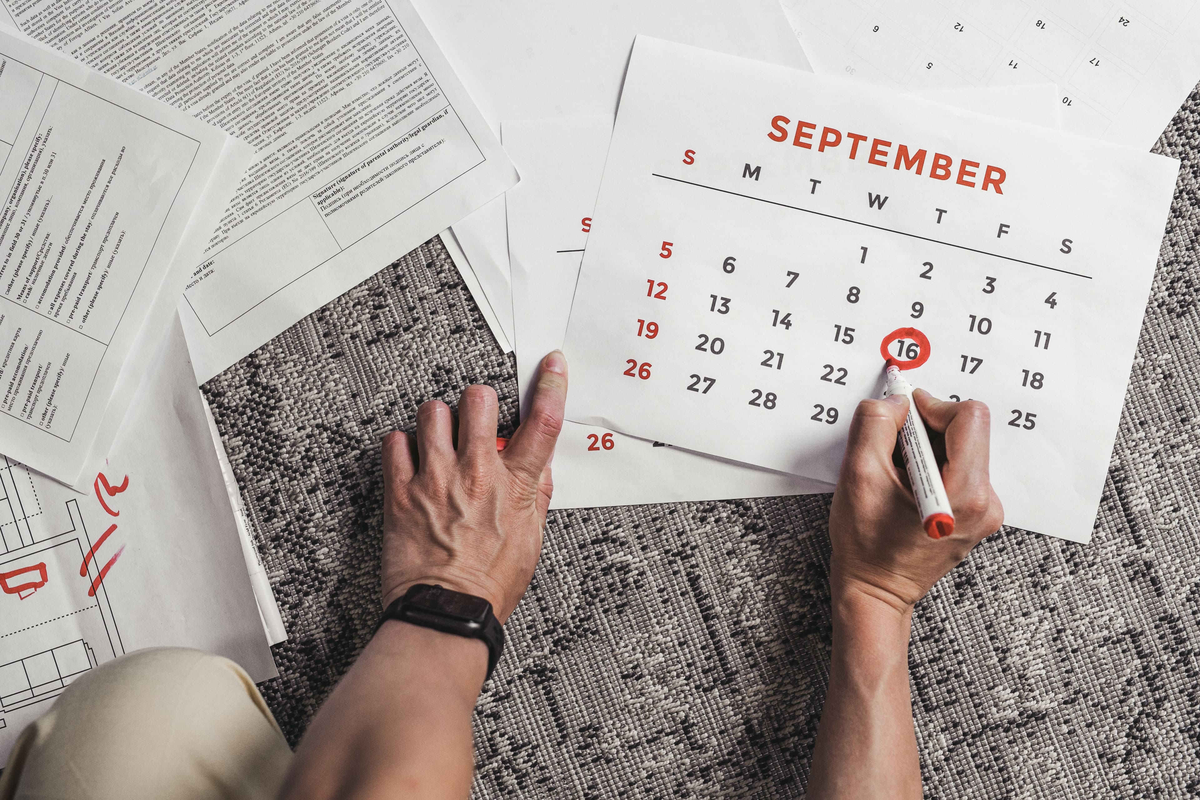 A hand circling a date on a calendar with a red marker