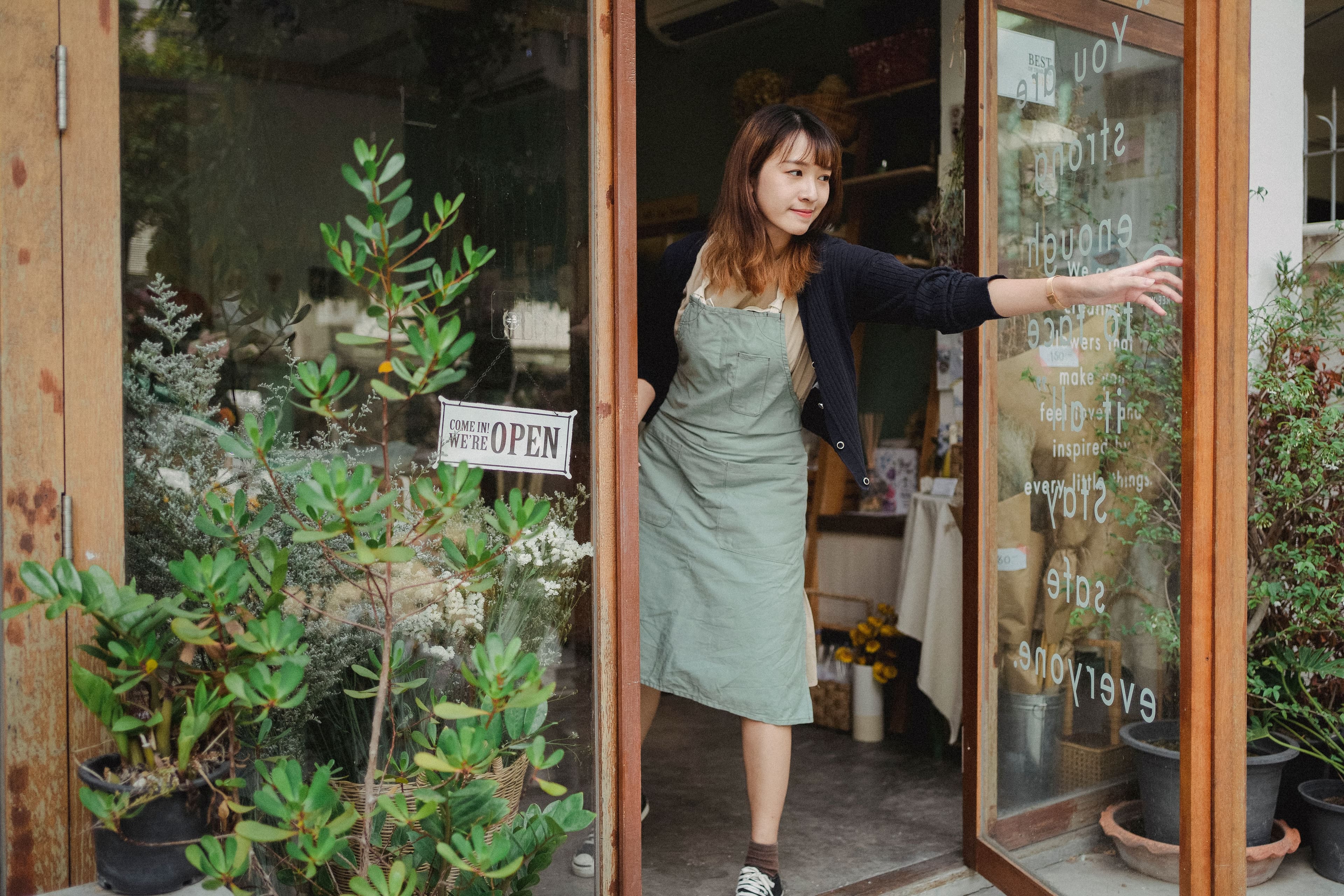 A small business owner opening the door of her shop