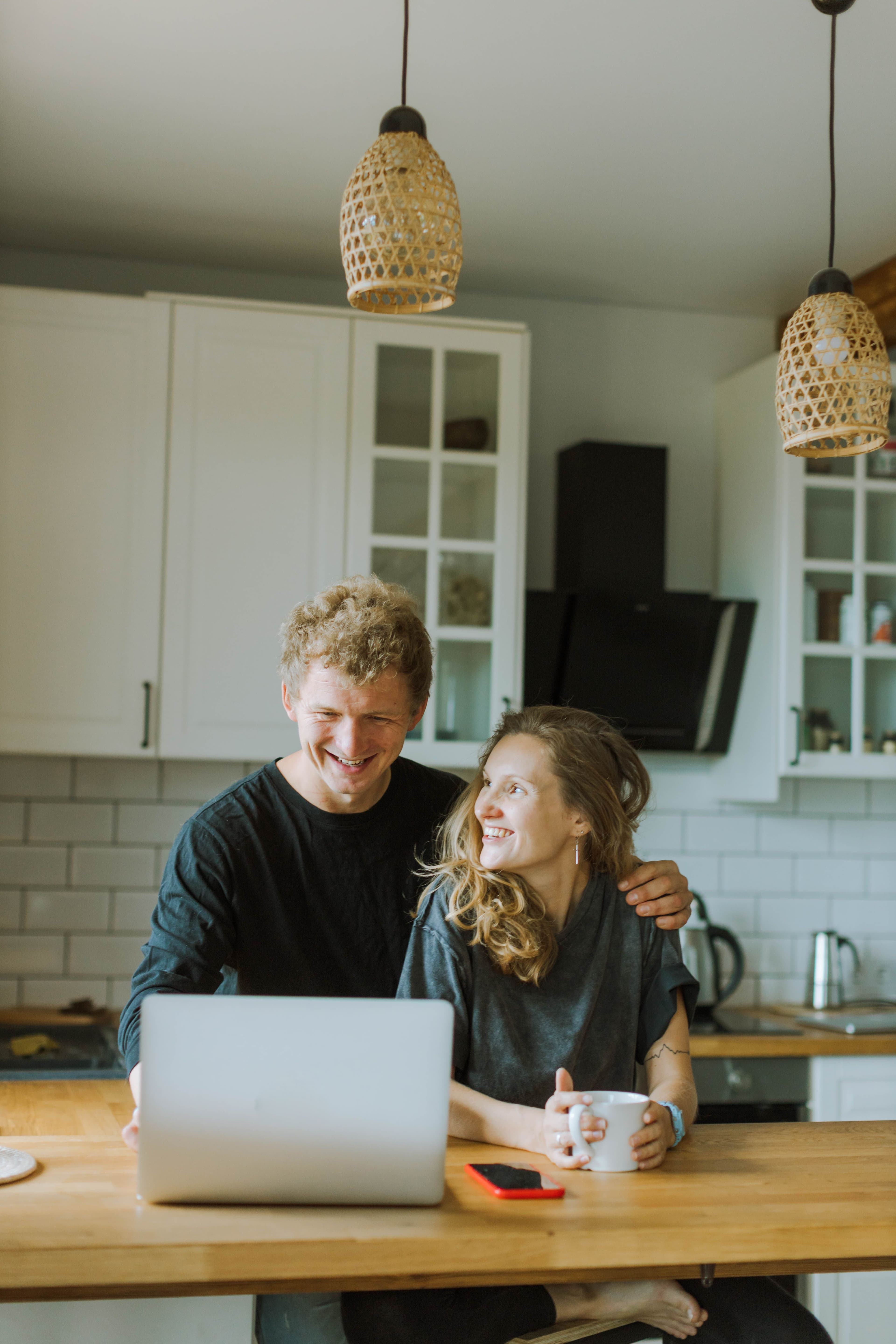 A smiling couple looking at a laptop together at their kitchen table