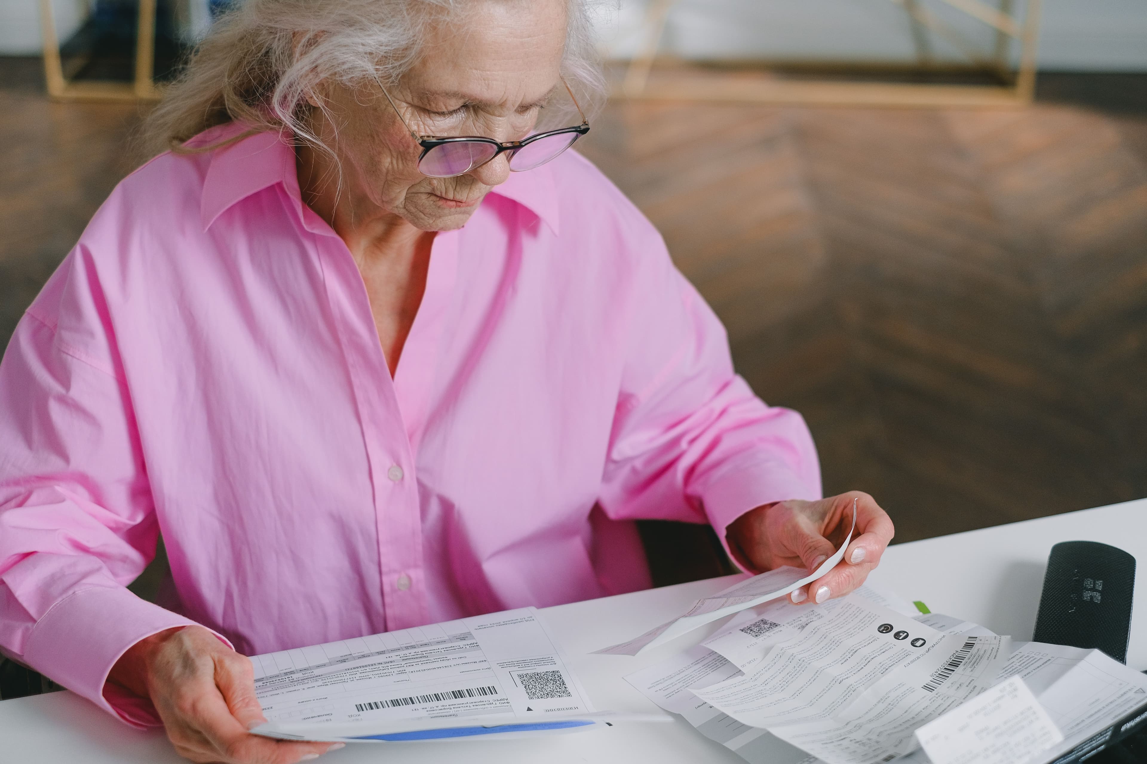 An older woman reviewing bills at a table