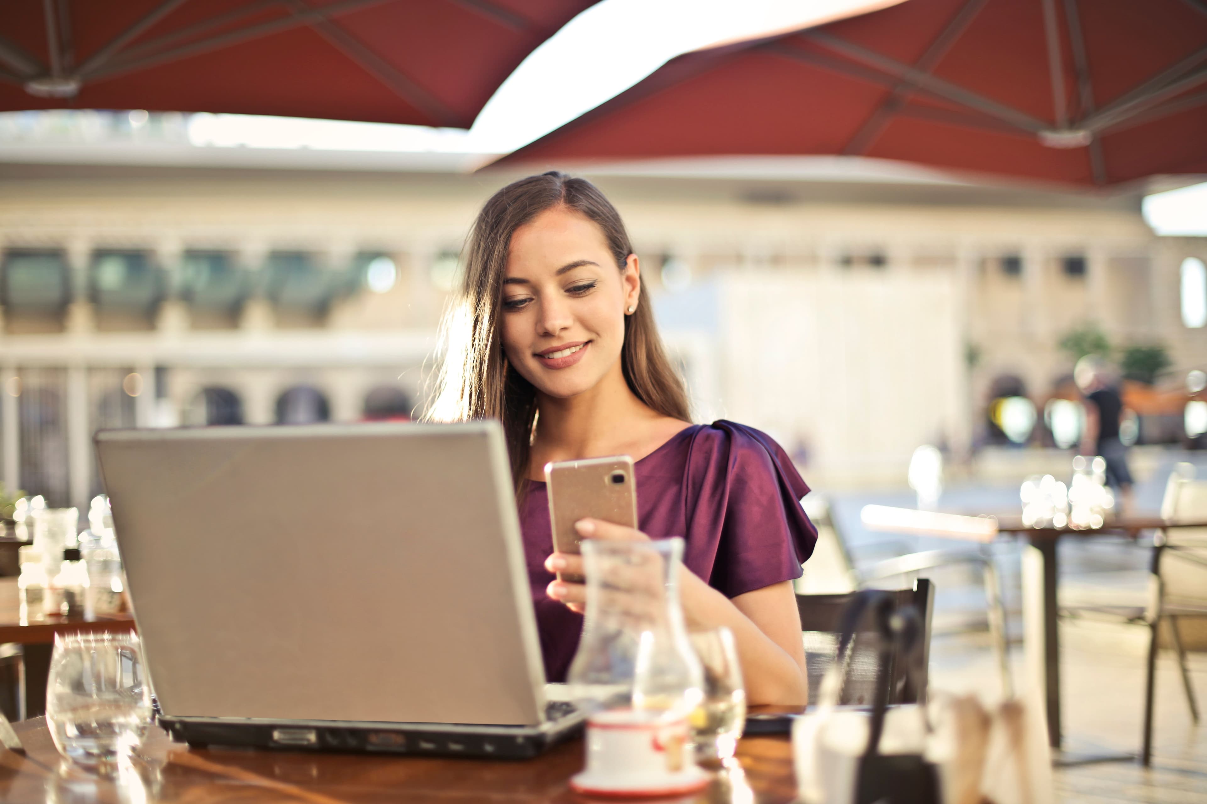 A freelancer working on a laptop and phone at an outdoor café