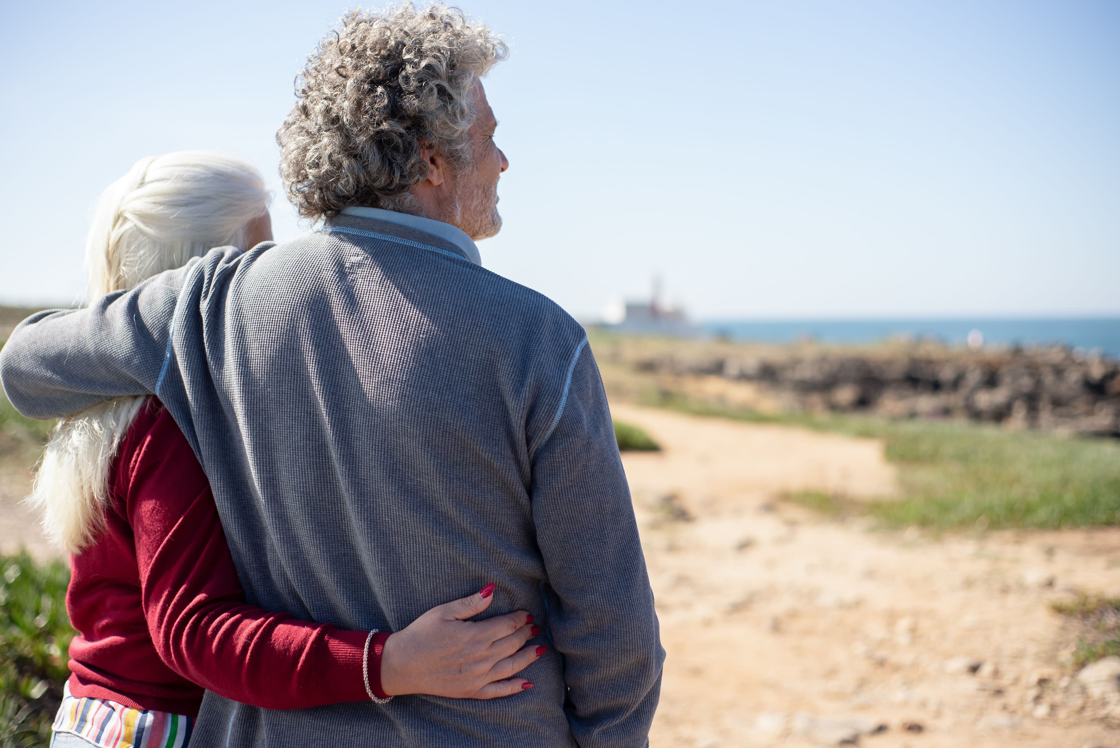 An older couple embracing while looking out over the coast